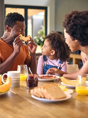 Young family sat down eating breakfast together in the morning